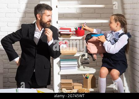 Écolière étudiant en classe avec professeur. Père expliquant ses devoirs à sa fille à la maison. Faire ses devoirs avec papa. Banque D'Images