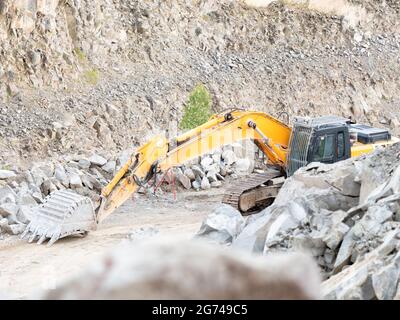 Pelle hydraulique pendant les travaux de terrassement dans des mines à ciel ouvert sur fond de carrière de gravier. Chargeuse avec godet abaissé en carrière. Pelle rétro creusant le groun Banque D'Images