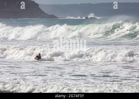 Le surfeur australien se dirige vers le rivage avec de grandes vagues à Palm Beach à Sydney, en Australie Banque D'Images