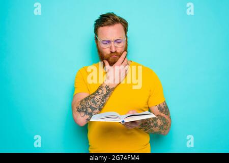 Un homme avec un t-shirt jaune lit un livre Banque D'Images