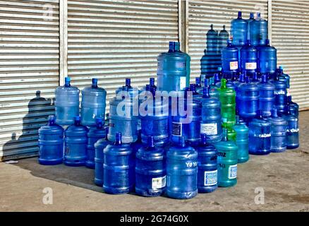 Cebu City, Philippines ; 2 décembre 2015 -- les conteneurs d'eau vides des clients s'empilent et attendent l'ouverture de cette station de remplissage d'eau locale. Banque D'Images
