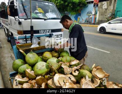 Mandaue City, Philippines ; 28 juillet 2016 -- scène pré-pandémique d'un vendeur itinérant vendant de la viande de noix de coco fraîche et de l'eau de noix de coco sur son chariot. Banque D'Images