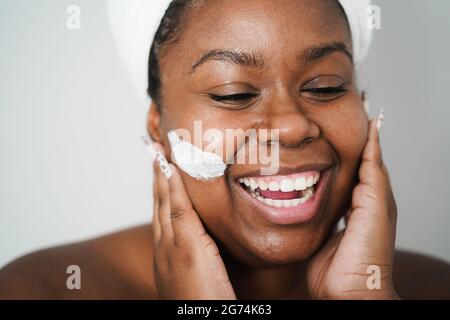 Jeune femme africaine portant un masque de peau - traitement de beauté et de soins du corps concept - foyer principal sur l'oeil gauche Banque D'Images