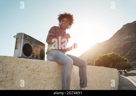 Homme afro-américain écoutant de la musique avec stéréo boombox vintage en extérieur sur la plage - Focus sur le visage Banque D'Images