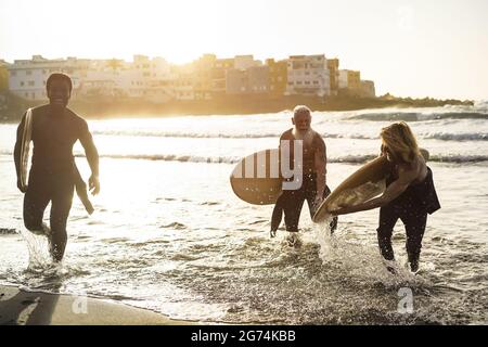 Amis surfeurs multigénérationnels s'amuser tout en surfant sur la plage - attention douce sur l'homme droit Banque D'Images