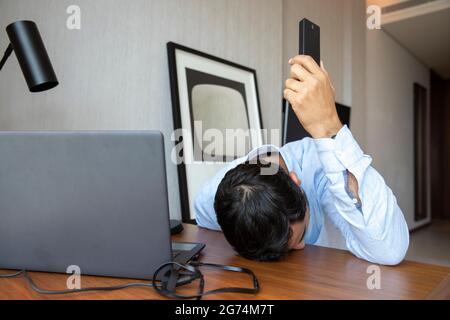 un homme fatigué d'âge moyen s'est endormi alors qu'il était au téléphone Banque D'Images