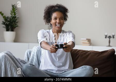 Femme afro-américaine excitée jouant au jeu vidéo, s'amusant Banque D'Images