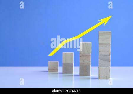 Tendance avec flèche jaune vers le haut des cubes en bois empilés. Concept de marché haussier et de croissance. Banque D'Images