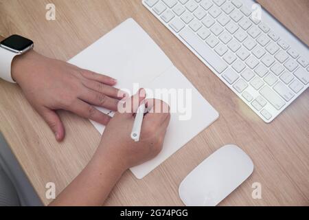 Un coup de tête de mains de femmes écrivant dans un carnet et un clavier sur la table Banque D'Images