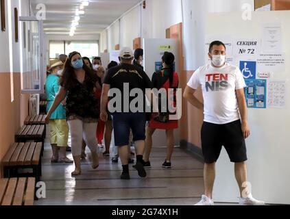 Les personnes ayant un masque utilisent un système de vote lors des élections législatives bulgares à Sofia, en Bulgarie, le 11 juillet 2021 Banque D'Images