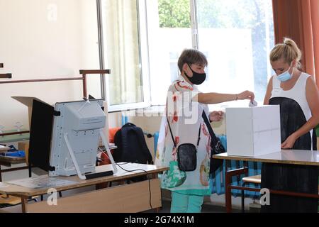 Les personnes ayant un masque utilisent un système de vote lors des élections législatives bulgares à Sofia, en Bulgarie, le 11 juillet 2021 Banque D'Images