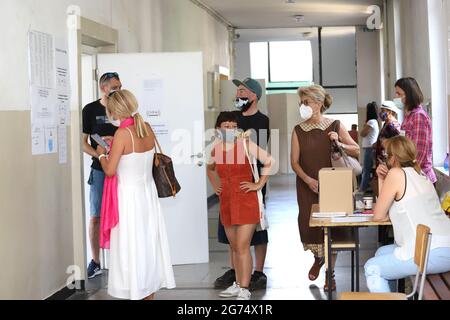 Les personnes ayant un masque utilisent un système de vote lors des élections législatives bulgares à Sofia, en Bulgarie, le 11 juillet 2021 Banque D'Images