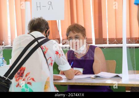 Les personnes ayant un masque utilisent un système de vote lors des élections législatives bulgares à Sofia, en Bulgarie, le 11 juillet 2021 Banque D'Images