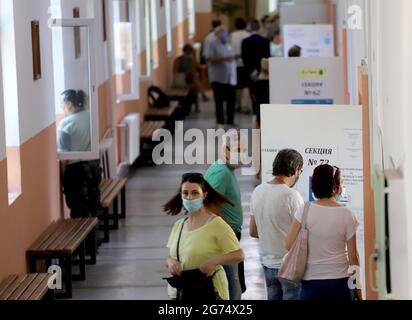 Les personnes ayant un masque utilisent un système de vote lors des élections législatives bulgares à Sofia, en Bulgarie, le 11 juillet 2021 Banque D'Images