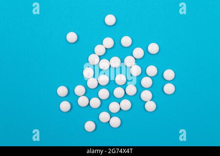 Industrie pharmaceutique mondiale et médicaments - pilules blanches sur fond bleu Banque D'Images