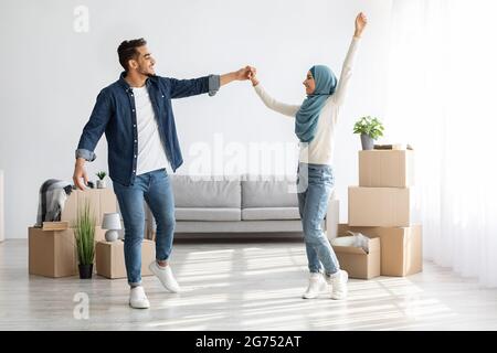 Homme et femme arabes joyeux dansant dans leur nouvelle maison Banque D'Images