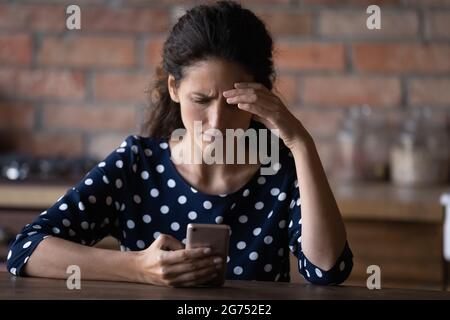 Inquiet Latino femme ayant des problèmes avec le téléphone mobile Banque D'Images
