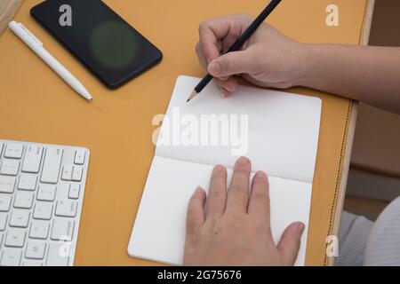 Un coup de tête de mains de femmes écrivant dans un carnet et un clavier sur la table Banque D'Images