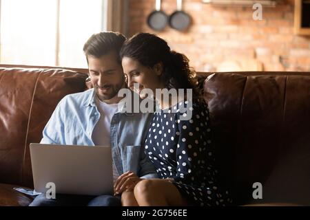 Couple heureux assis sur un canapé à la maison ensemble Banque D'Images