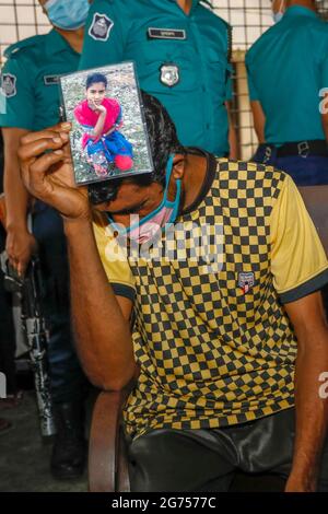 Un père tenant la photo de sa fille à l'hôpital du Dhaka Medical College pendant que les médecins collectent des échantillons de sang des parents de la victime Banque D'Images