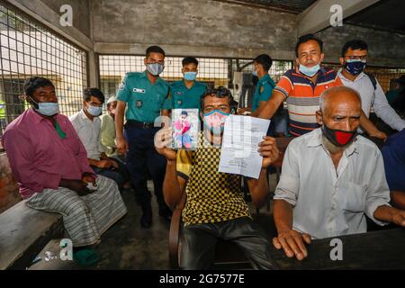 Un père tenant la photo de sa fille à l'hôpital du Dhaka Medical College pendant que les médecins collectent des échantillons de sang des parents de la victime Banque D'Images