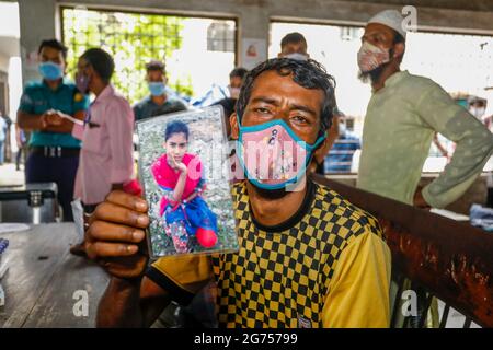 Un père tenant la photo de sa fille à l'hôpital du Dhaka Medical College pendant que les médecins collectent des échantillons de sang des parents de la victime Banque D'Images