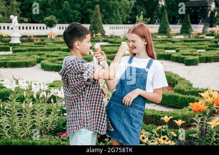 enfants adolescents garçon et fille ont plaisir le jour d'été sur fond de verdure, manger de la crème glacée Banque D'Images