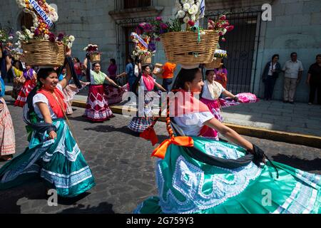 Oaxaca de Juarez, Mexique - 15 mai 2014 : un groupe de femmes portant des robes traditionnelles colorées et portant des paniers avec des fleurs, dansant dans une rue Banque D'Images