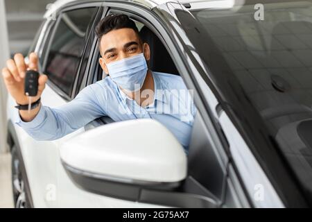 Homme musulman en masque protecteur achetant une nouvelle voiture Banque D'Images