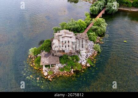 Vue aérienne d'une grande ruines abandonnées, maison, hôtel, tombant à des morceaux sur une petite île avec un pont près de Shkodra. Albanie, Balkans, Europe Banque D'Images