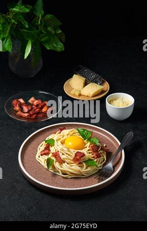 Pâtes italiennes traditionnelles Carbonara avec bacon, fromage et jaune d'œuf sur plaque sur fond sombre. Banque D'Images