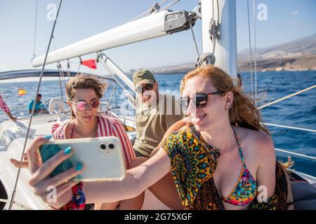 un groupe d'amis, deux femmes et un homme, prendre un selfie pendant une fête de bateau, les gens heureux pendant une journée d'été profiter de la vie, concept de togetherness. Banque D'Images