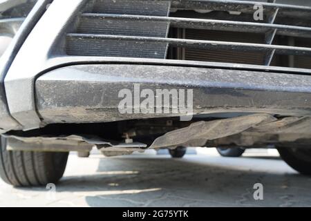 Gros plan d'un fond endommagé d'une voiture noire sale. Une voiture de luxe moderne en service comme vu d'en dessous. Banque D'Images