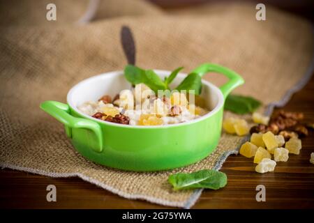 flocons d'avoine sucrés cuits, avec noix et fruits confits un bol sur une table en bois Banque D'Images