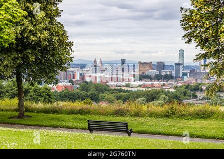 Un banc vu entre des arbres surplombant les gratte-ciel de Liverpool depuis Everton Park. Banque D'Images