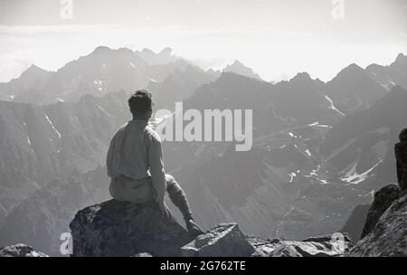 1935, historique, un randonneur mâle assis sur un rocher prenant dans la vue, regardant les chaînes de montagnes des Sudètes ou des Sudètes dans la Tchécoslovaquie avant la Seconde Guerre mondiale, la plus haute altitude étant le mont Snezka. À cette époque, les gammes et les massifs individuels étaient situés dans une région connue sous le nom de Sudetenland, une région qui abrite une majorité de peuples germanophones. En 1938, le Sudetenland a été annexé à l'Allemagne par le biais du Pacte de Munich. WW2 a commencé un an plus tard. Banque D'Images