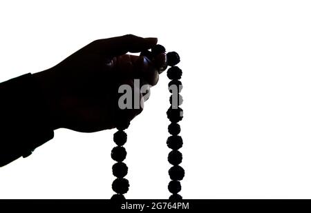 Image de silhouette des perles de prière en main. Main masculine tenant rosaire, priant à dieu sur fond blanc, spiritualité religieuse. Homme tenant le rosaire bea Banque D'Images