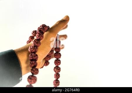 Image des perles de prière en main. Main masculine tenant rosaire, priant à dieu sur fond blanc, spiritualité religieuse. Homme tenant des perles rosaires et medi Banque D'Images