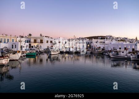 Grèce, île de Paros Vieux port de Naousa. 19 mai 2021. Cyclades. Des bateaux de pêche typiques amarrés au quai du port, des touristes dans un café en plein air traditionnel an Banque D'Images