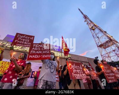 Des journalistes philippins, des activistes de la liberté de la presse, des partisans et des employés de l'ABS-CBN, le plus grand réseau de diffusion du pays, portent des signes pour protester contre le premier anniversaire du rejet d'une nouvelle franchise pour le réseau de radiodiffusion devant son siège à Quezon City, dans la région métropolitaine de Manille. Le 10 juillet 2021, le Congrès philippin a voté le rejet d'une nouvelle franchise pour le réseau multimédia ABS-CBN, après l'expiration de sa franchise de 25 ans. Philippines. Banque D'Images