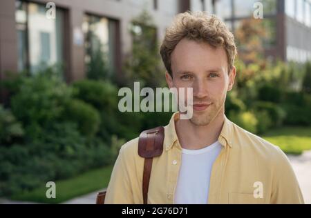 Portrait de beau homme confiant portant une chemise jaune décontractée regardant l'appareil photo debout dans la rue, espace de copie. Concept d'entreprise réussi Banque D'Images