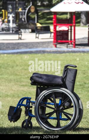 Image verticale d'un fauteuil roulant noir au milieu de l'herbe derrière le parc Banque D'Images
