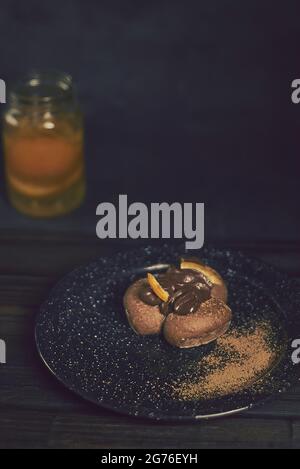 Un cliché vertical de dessert au chocolat plaqué avec de la poudre de cacao et une boisson à l'orange en arrière-plan Banque D'Images