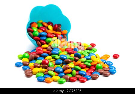 Boutons de chocolat enrobés de bonbons de couleur arc-en-ciel dans un bol bleu amusant sur fond blanc Banque D'Images