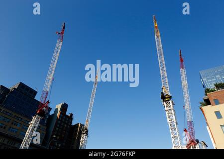 Quatre grues à tour de luffing contre un ciel bleu ensoleillé sans nuages sur un chantier de construction dans le quartier de Tribeca à Manhattan, New York, NY. Banque D'Images