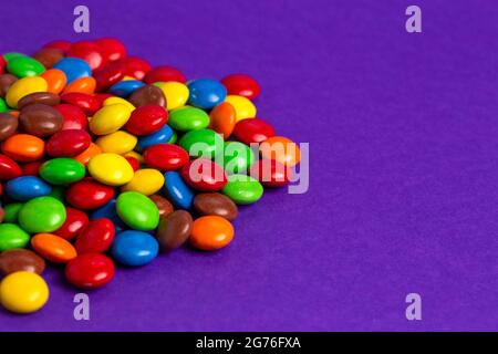 Pile de boutons en chocolat enrobés de bonbons de couleur arc-en-ciel Banque D'Images