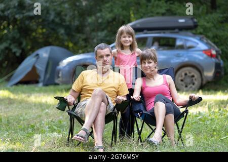 De jeunes parents heureux et leur fille se reposent ensemble sur le camping en été. Banque D'Images