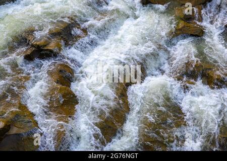 Vue aérienne de la cascade de la rivière avec de l'eau turquoise claire tombant entre des blocs mouillés avec de la mousse blanche épaisse. Banque D'Images