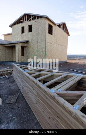 Pile de pièces de bois à côté d'une maison presque finie dans un nouveau quartier Banque D'Images