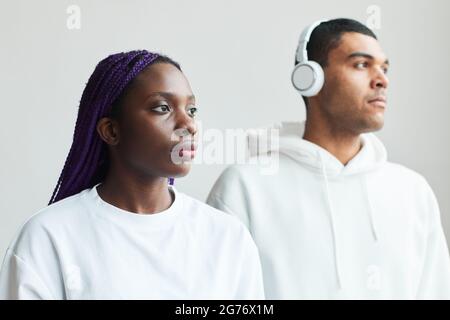 Portrait graphique minimal d'un jeune couple de race mixte portant du blanc en posant à l'appareil photo Banque D'Images